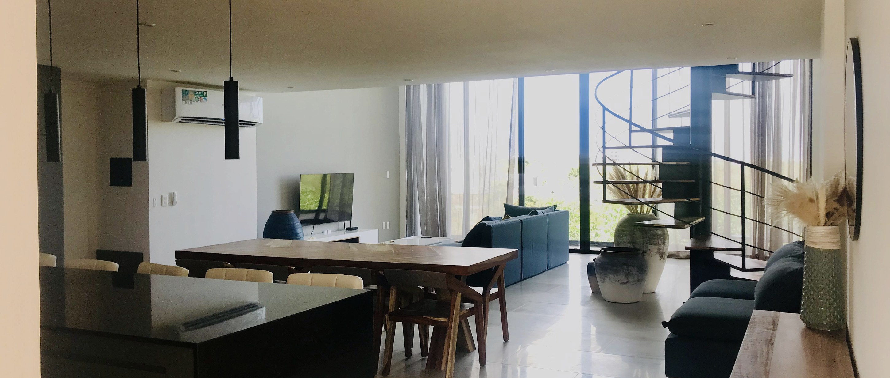 Departamento de doble altura con escalera de caracol y ventanal a la vegetación